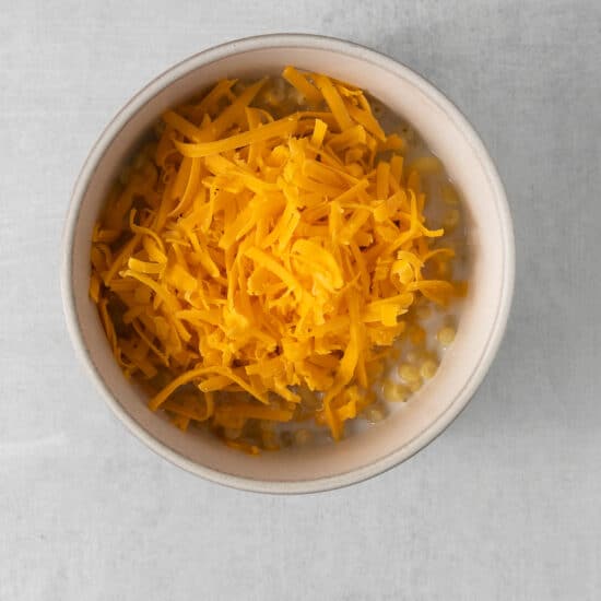shredded cheese in a bowl on a gray background.