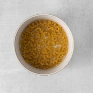 a bowl of pasta sitting on a concrete surface.