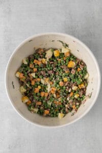 a white bowl filled with peas, carrots and meat.