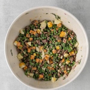 a white bowl filled with peas, carrots and meat.