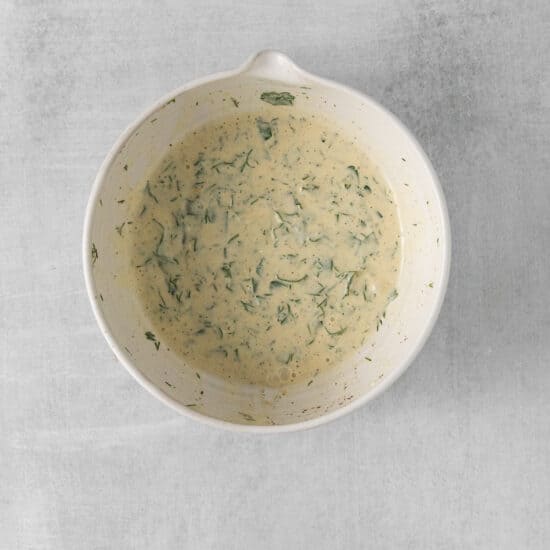 a white bowl with a green sauce on it.