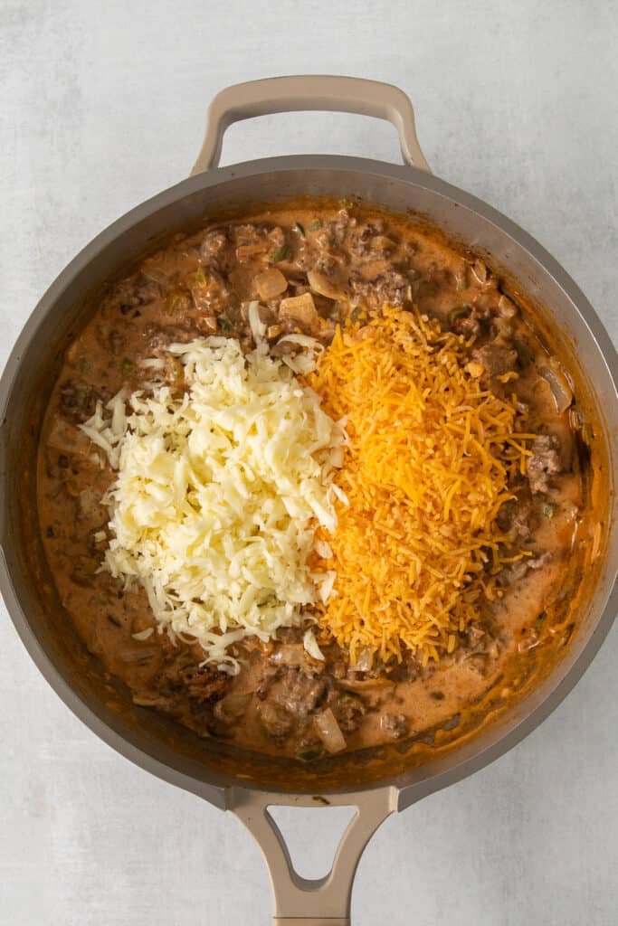 Taco meat topped with shredded cheese in a skillet.