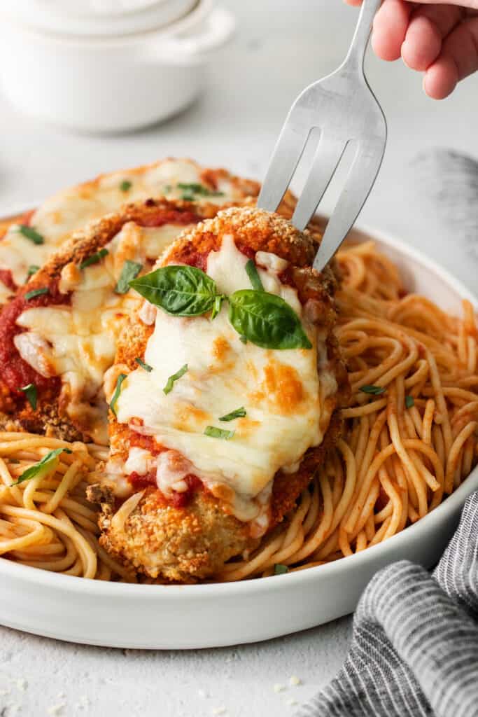 chicken parmigiana on a plate with a fork.