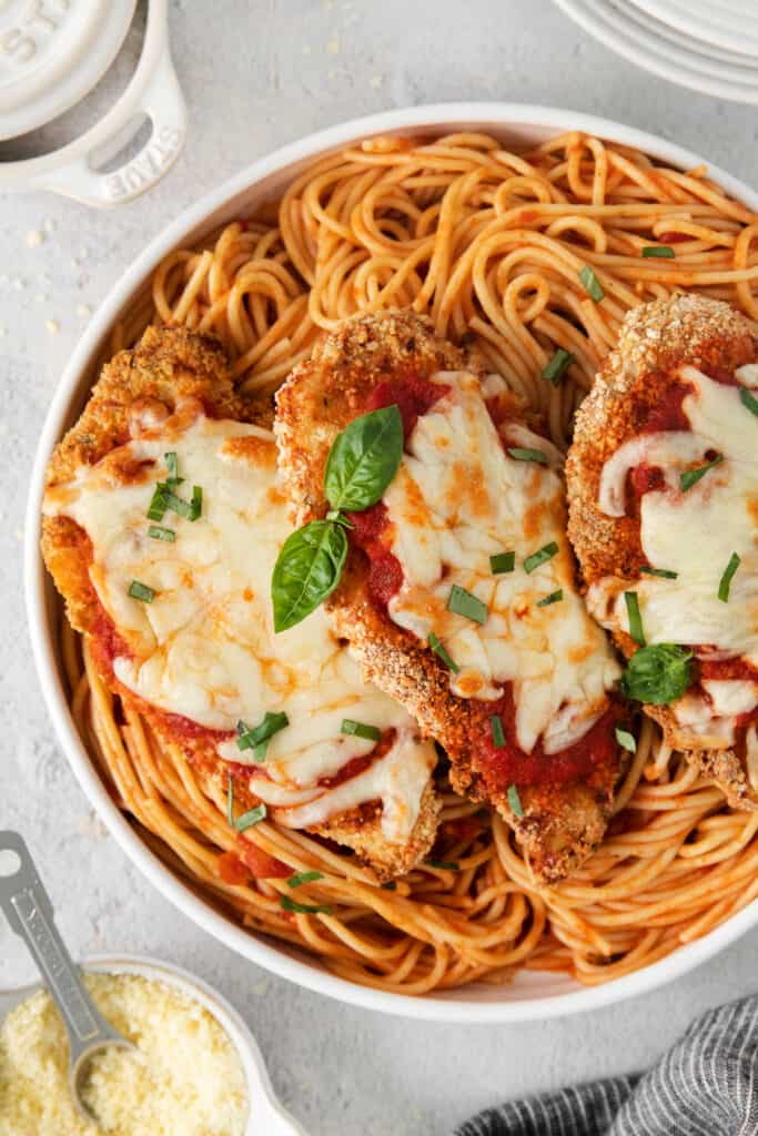 chicken parmigiana in a white dish with parmesan cheese.