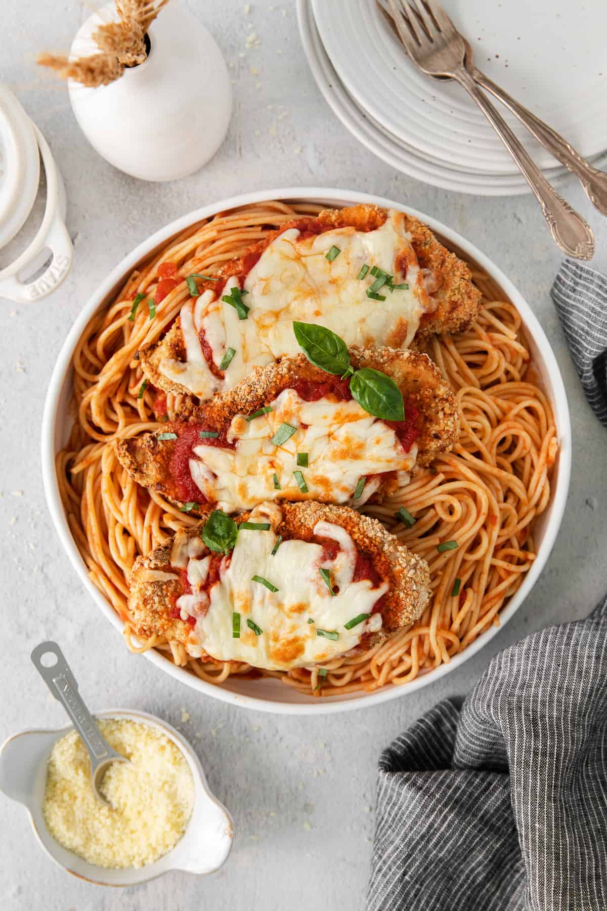 chicken parmigiana in a white dish with parmesan cheese.