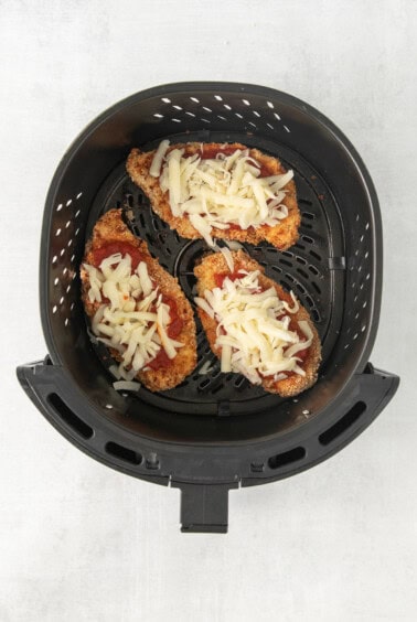 a pizza in an air fryer with cheese on it.