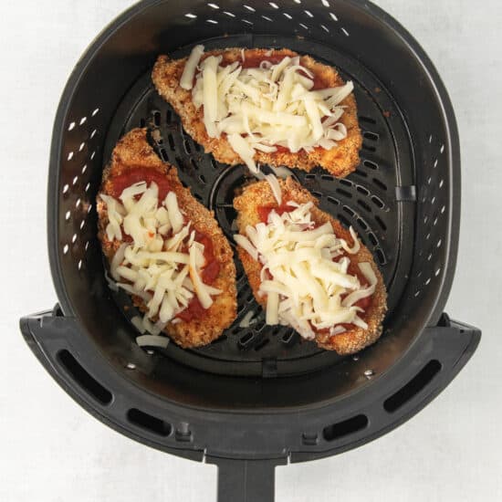 a pizza in an air fryer with cheese on it.