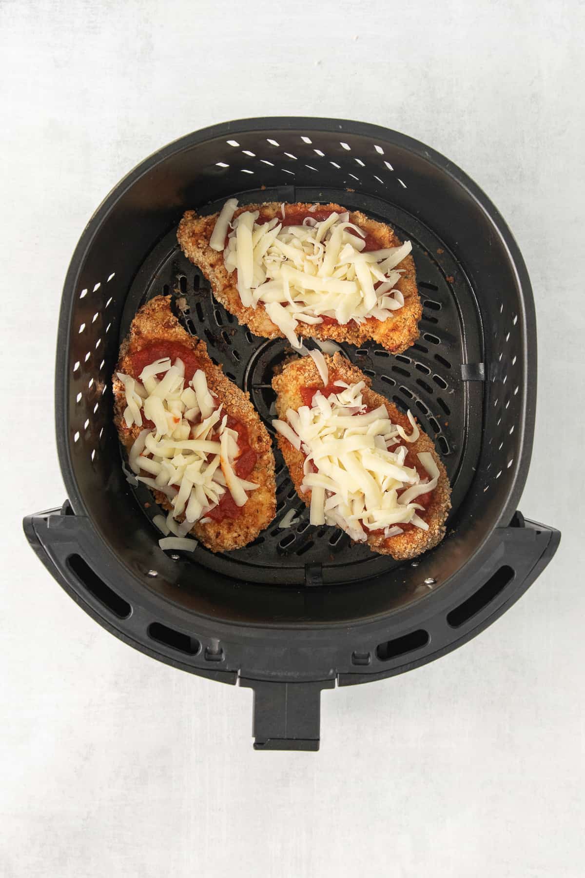 a pizza in an air fryer with cheese on it.