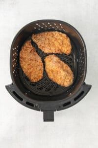 two chicken breasts in an air fryer.