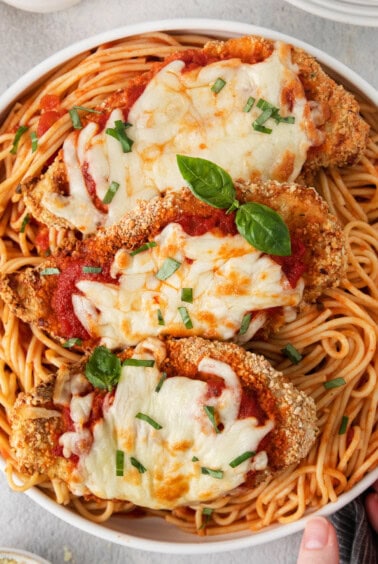 a bowl of spaghetti with chicken parmigiana.