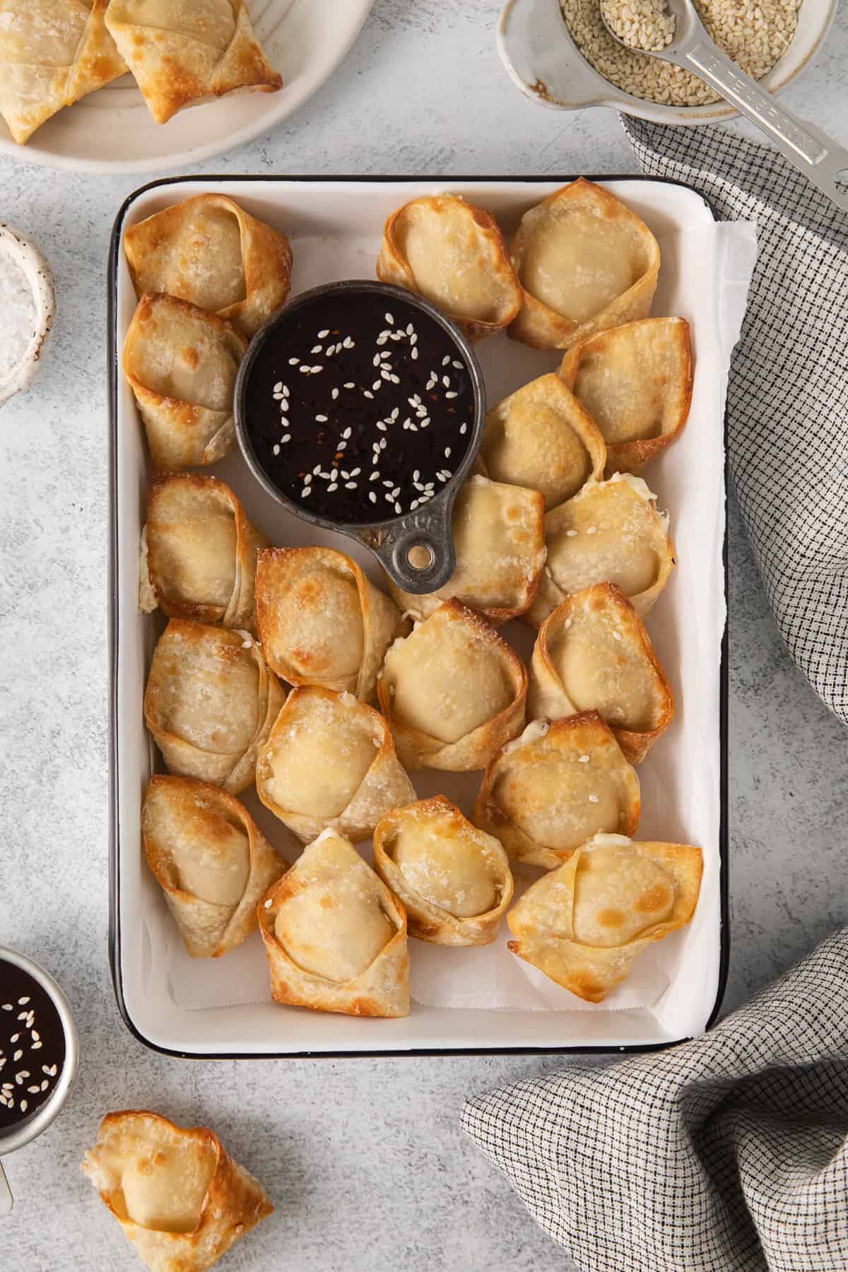 a tray of fried dumplings with sauce and sesame seeds.