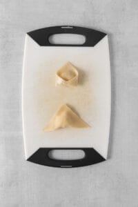 a cutting board with two pieces of dumplings on it.