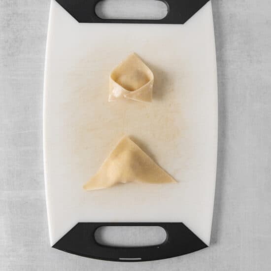 a cutting board with two pieces of dumplings on it.