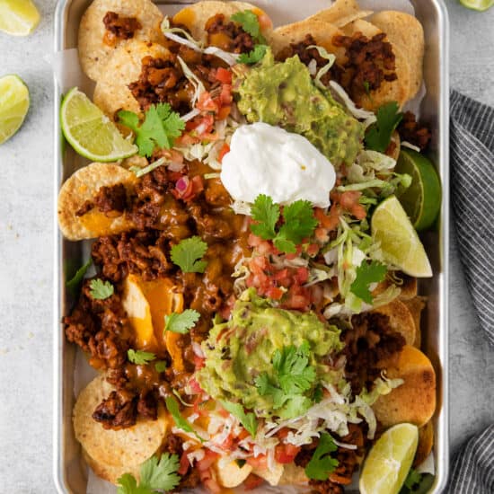 a tray of nachos with guacamole and sour cream.