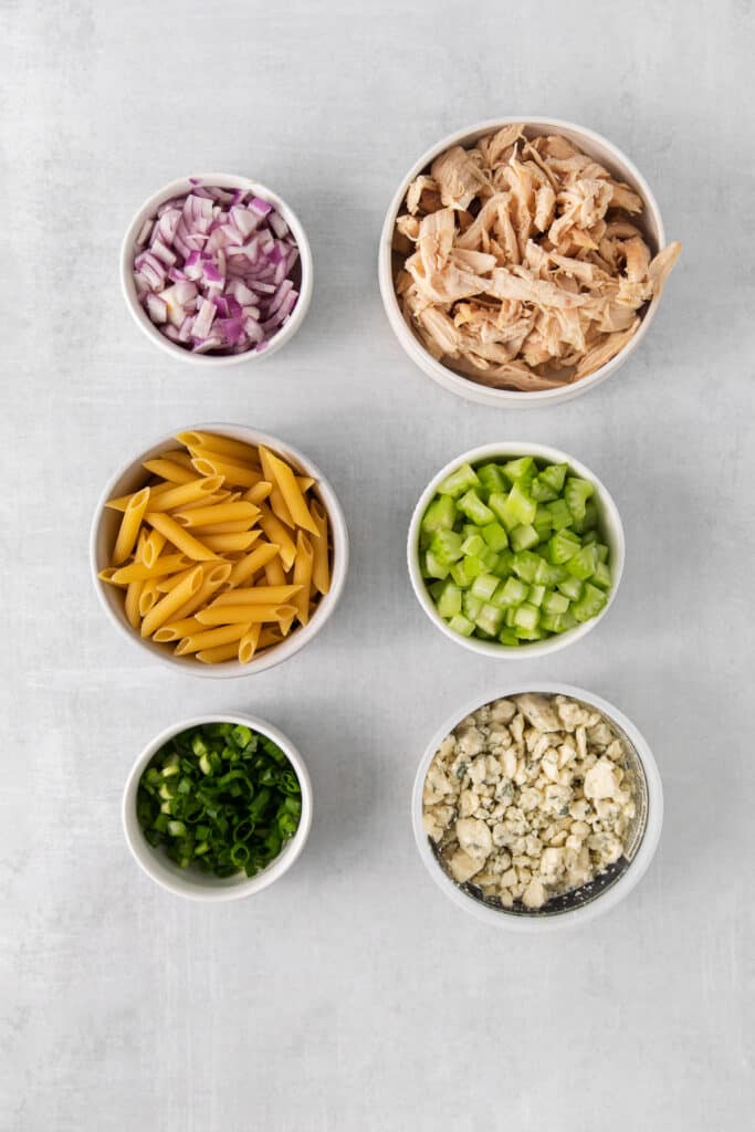 Ingredients for buffalo chicken pasta salad in bowls.