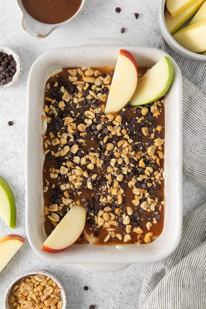 a white baking dish with apples, nuts, and granola.