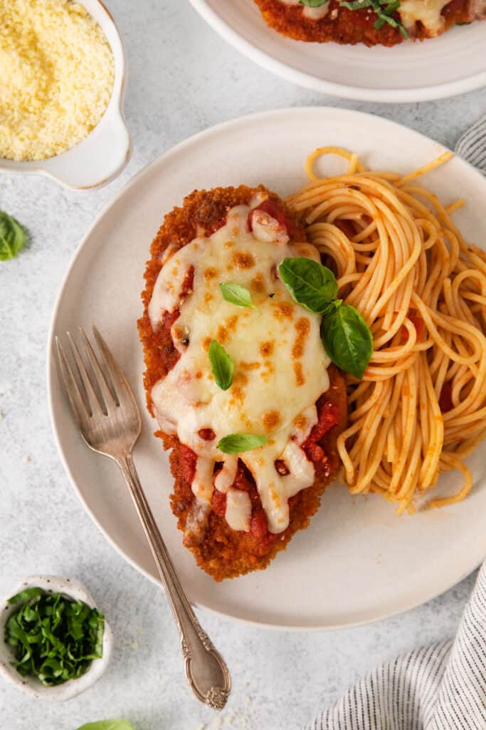 Chicken parmesan on a plate with pasta.