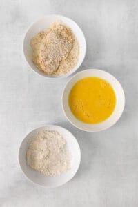 three bowls containing flour, eggs and orange juice.