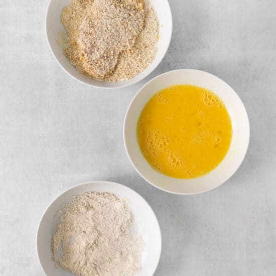 three bowls containing flour, eggs and orange juice.