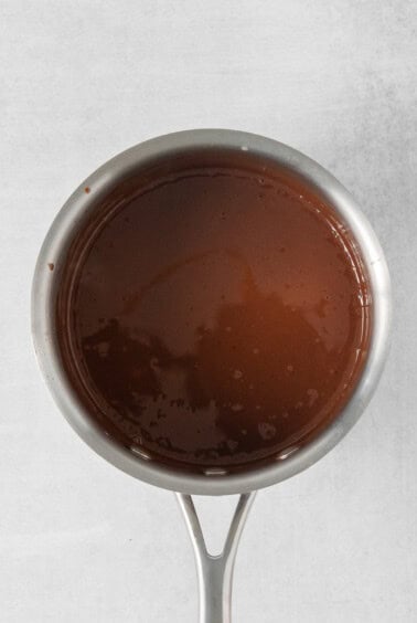 chocolate sauce in a metal pan on a white surface.