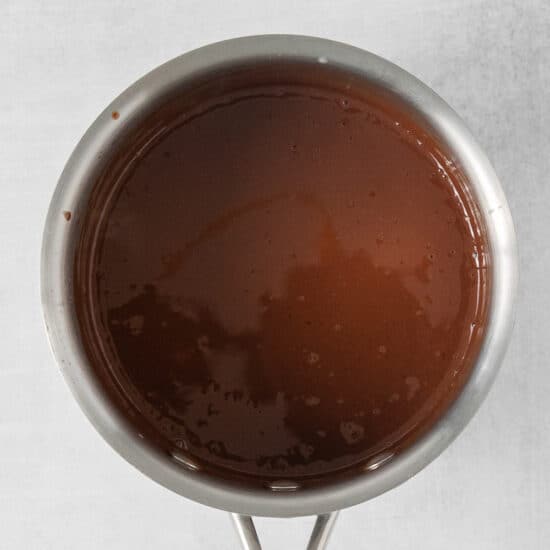 chocolate sauce in a metal pan on a white surface.