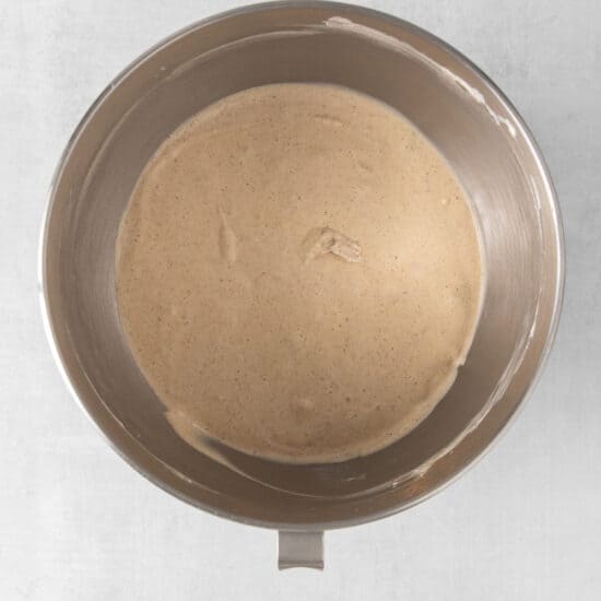 a metal bowl filled with brown batter on a white surface.