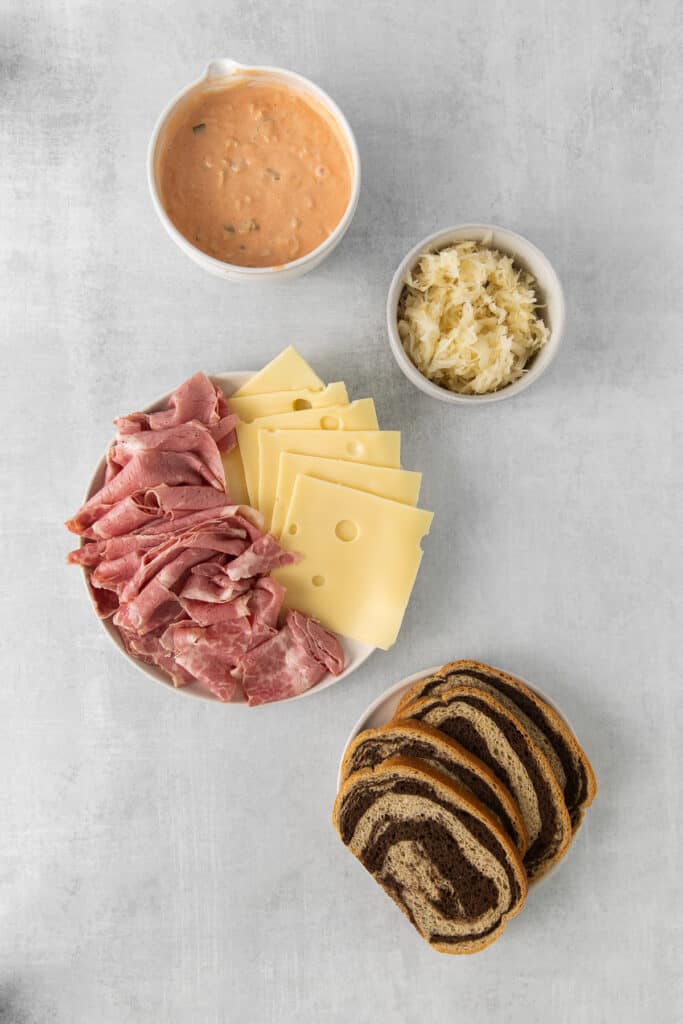 a plate with ham, cheese, bread and dip.