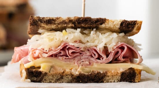 a sandwich with ham and sauerkraut on a wooden board.