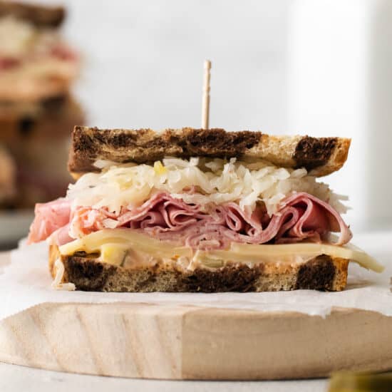a sandwich with ham and sauerkraut on a wooden board.