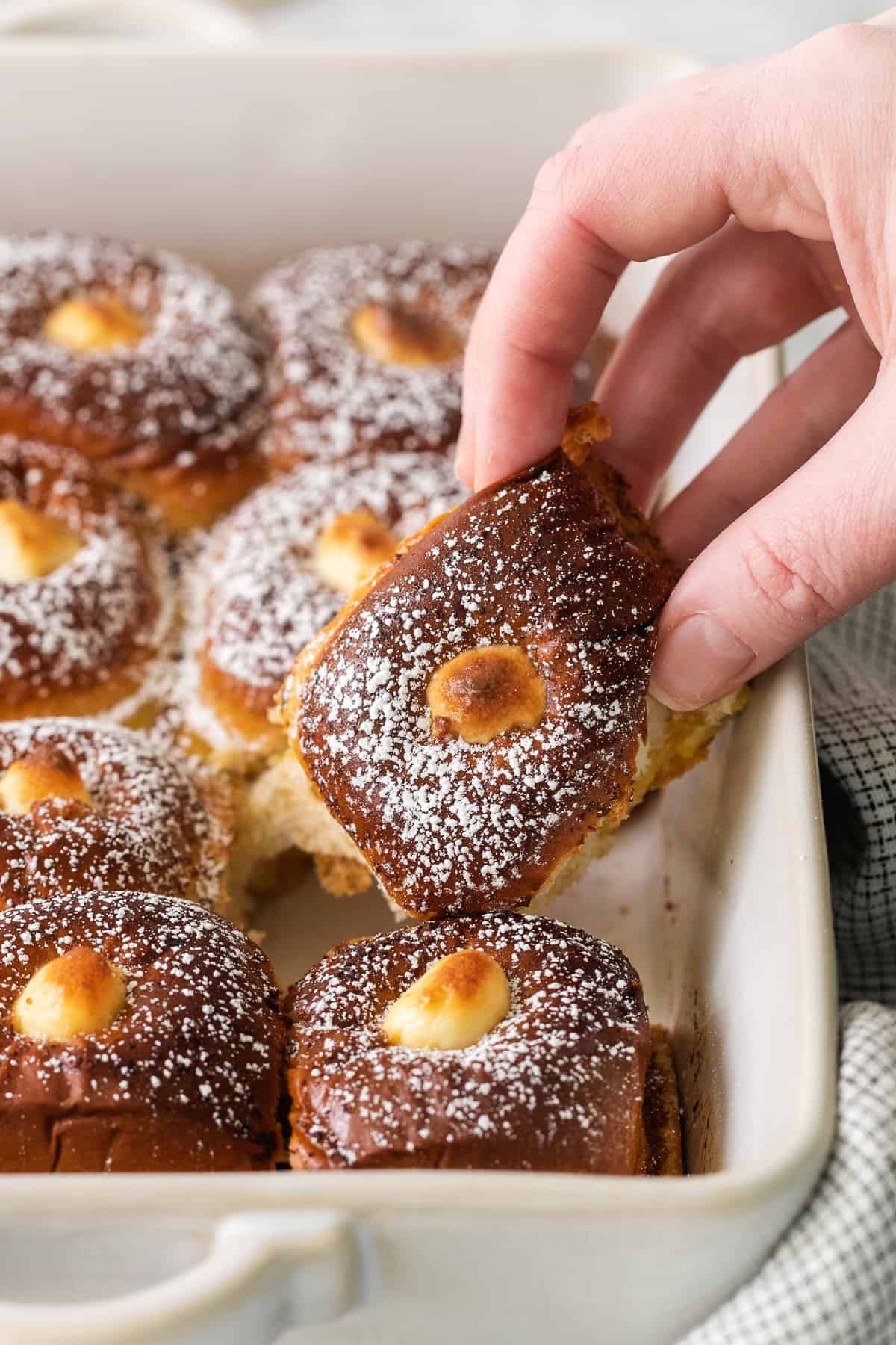 A hand grabbing a hawaiian roll stuffed french toast.