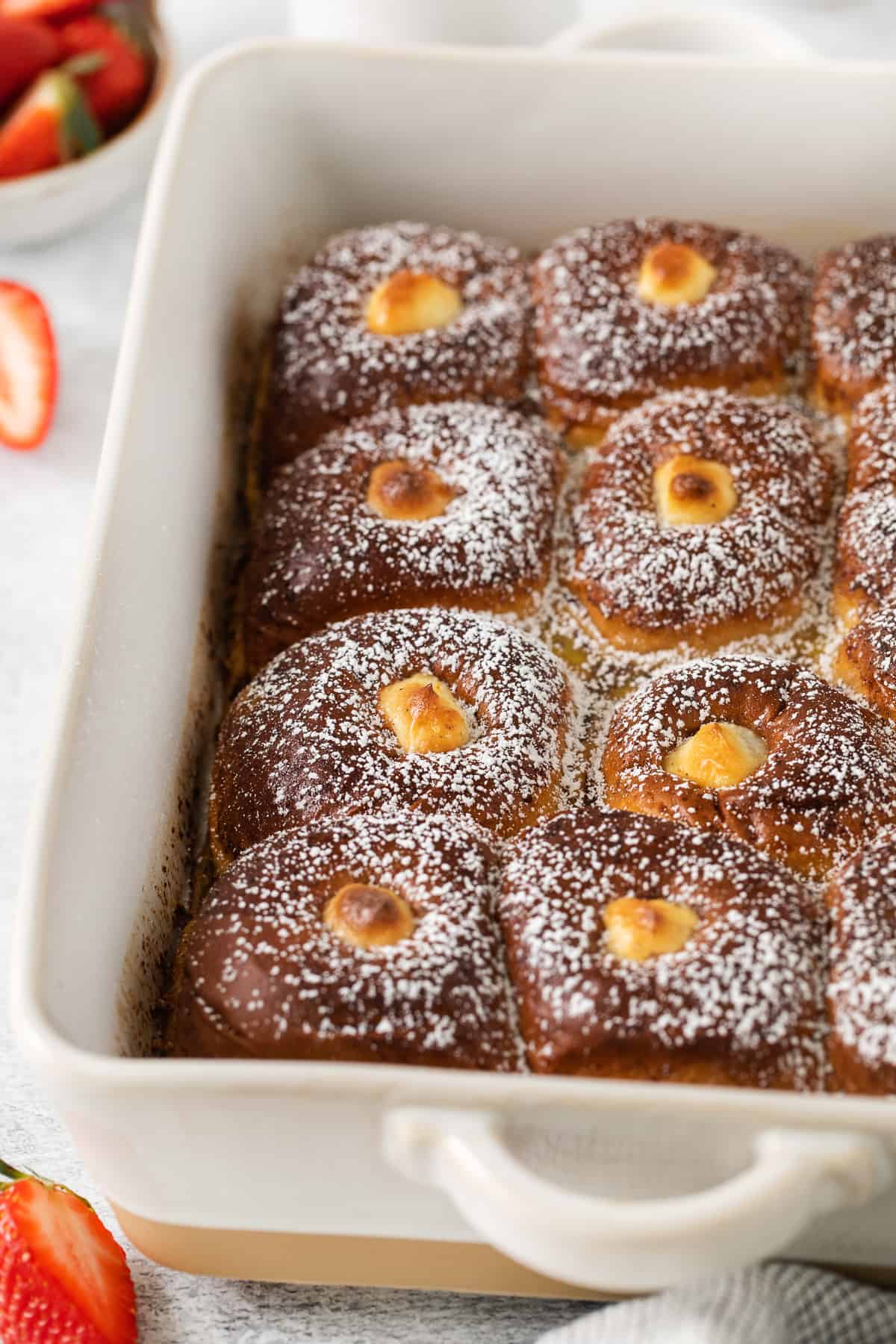 Stuffed hawaiian roll french toast in a casserole dish.