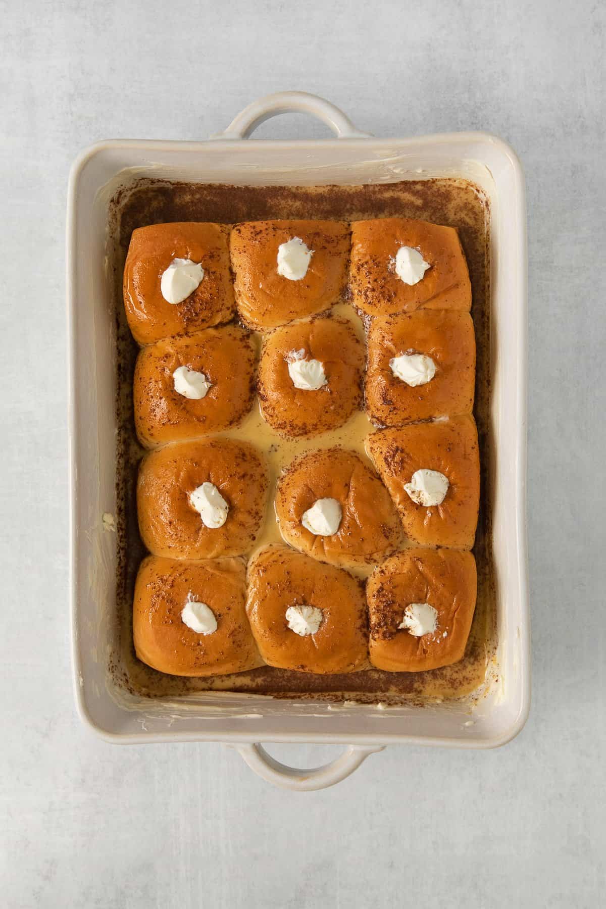 Hawaiian roll stuffed french toast in a casserole dish.