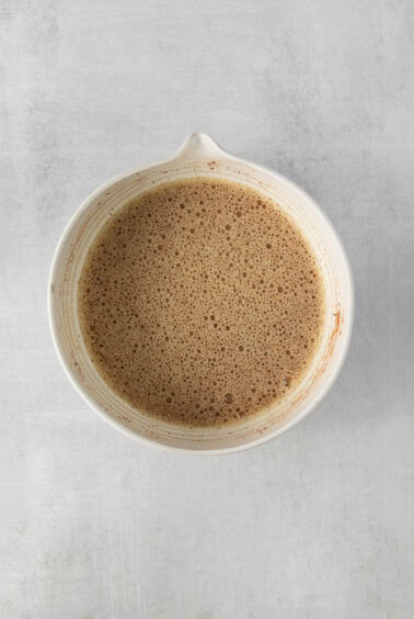 a white bowl of coffee on a gray surface.