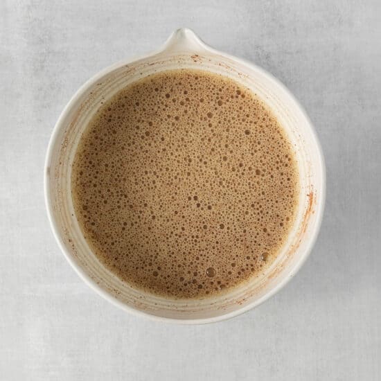 a white bowl of coffee on a gray surface.