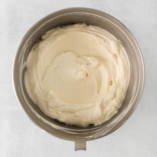 whipped cream in a bowl on a white surface.