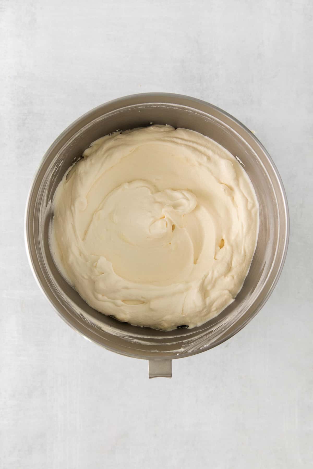 whipped cream in a bowl on a white surface.