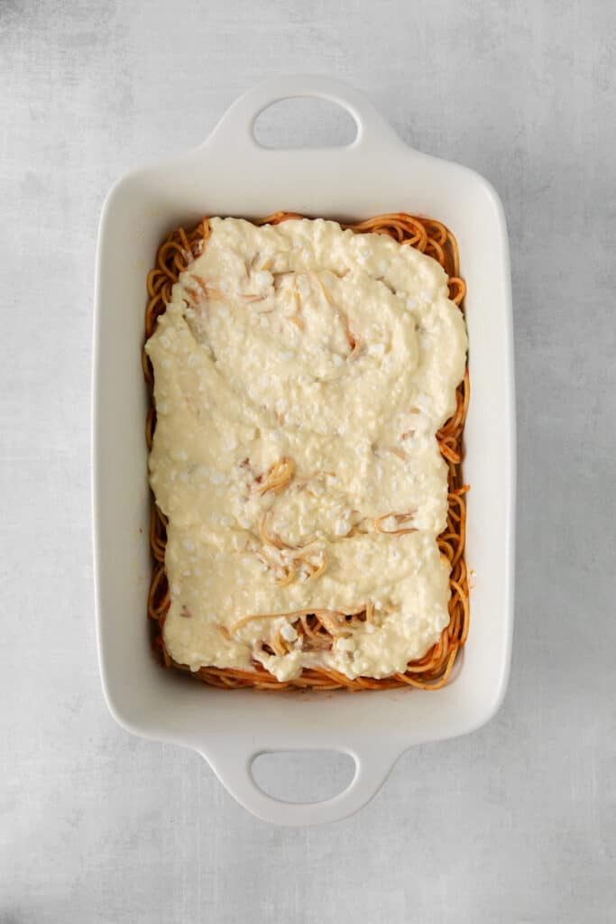 Spaghetti covered in a cheese sauce in a casserole dish.