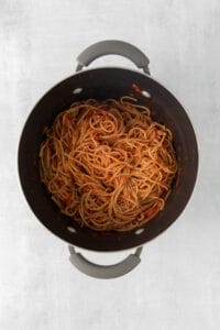 a pot filled with spaghetti on a white surface.