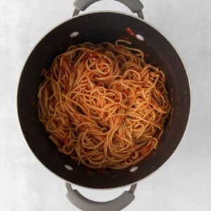 a pot filled with spaghetti on a white surface.