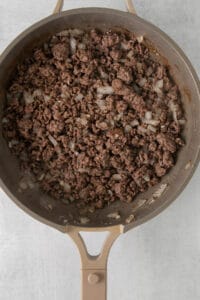 a frying pan filled with ground beef and onions.