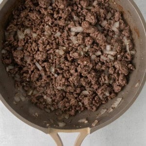 a frying pan filled with ground beef and onions.