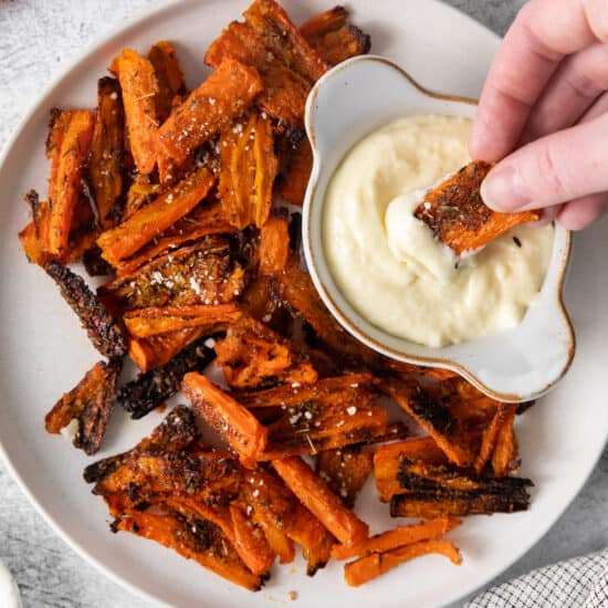 Parmesan smashed carrots on a plate with aioli dipping sauce.