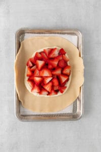 a pie crust with strawberries on it on a baking sheet.