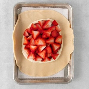 a pie crust with strawberries on it on a baking sheet.