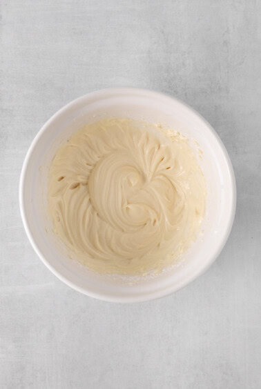whipped cream in a white bowl on a gray background.