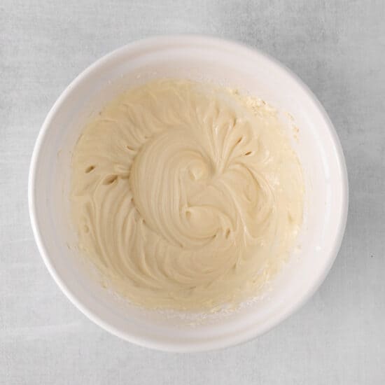 whipped cream in a white bowl on a gray background.