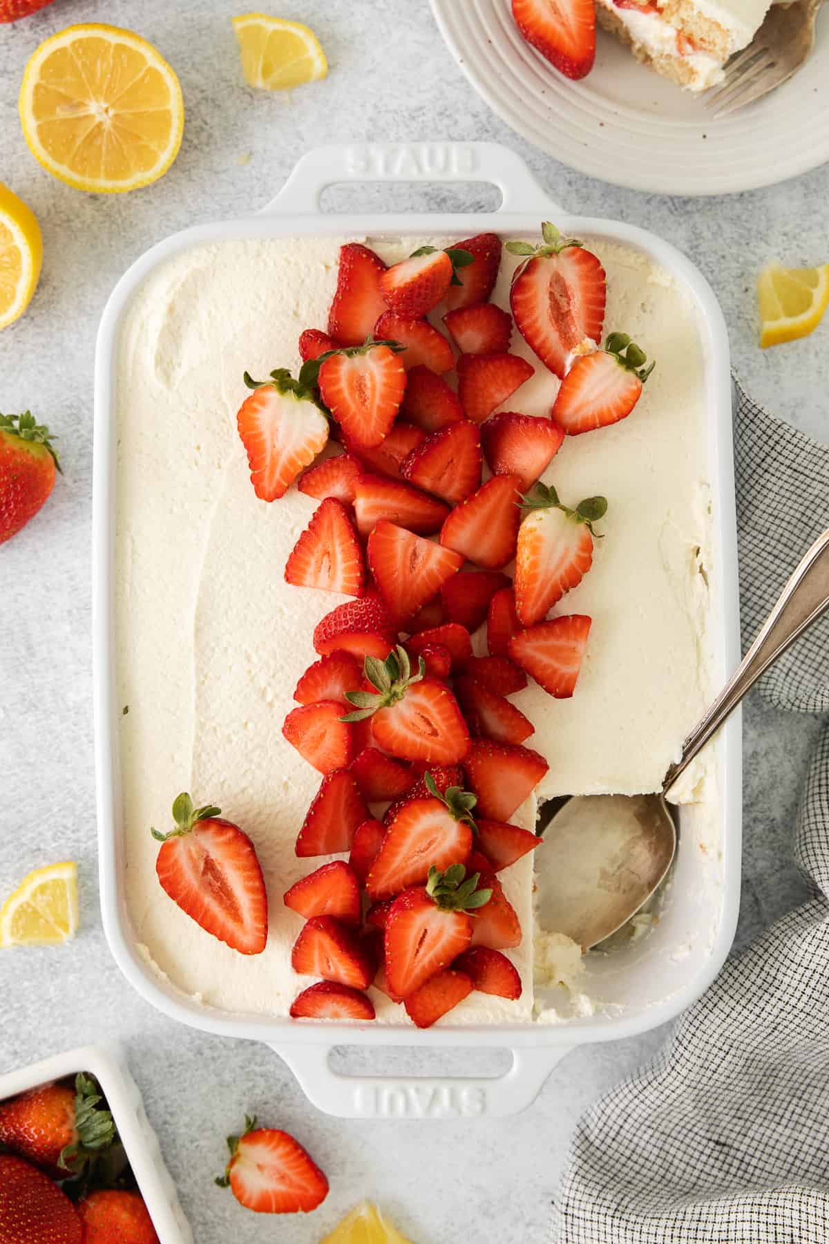 Strawberry tiramisu in a baking dish with a spoon.