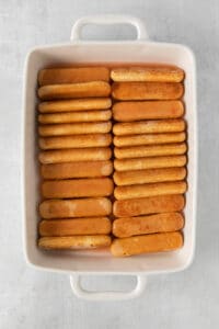 a white dish filled with crackers on a grey background.