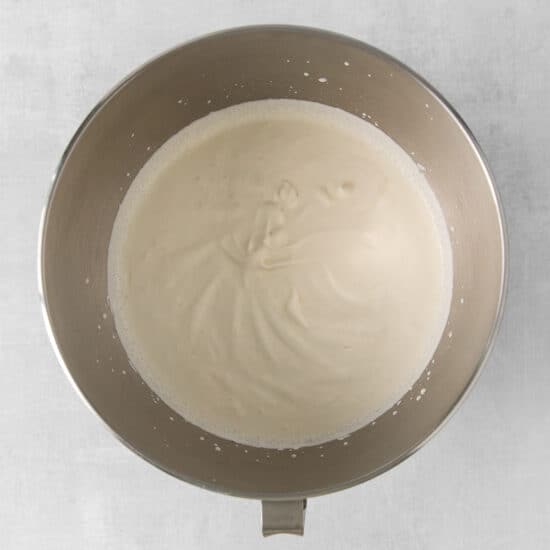 whipped cream in a metal bowl on a white background.