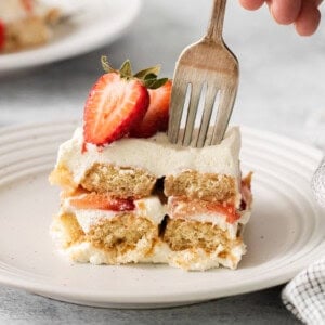 Slice of strawberry tiramisu on a plate with a fork.